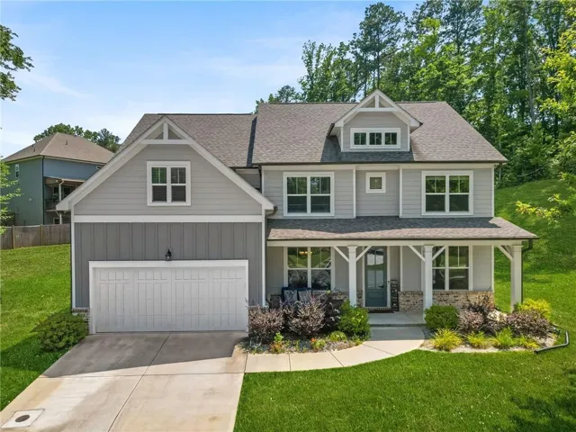 Light gray siding exterior with a two-car garage, covered front porch, stone accents, and varied rooflines
