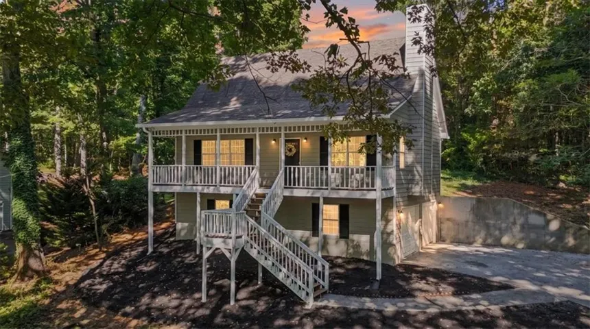 Two-story dwelling with siding exterior, multiple elevated balconies, and a prominent exterior chimney