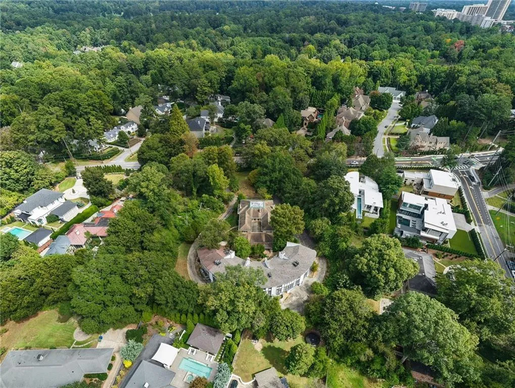 Expansive property surrounded by mature trees, featuring a paved driveway, and multiple residential structures
