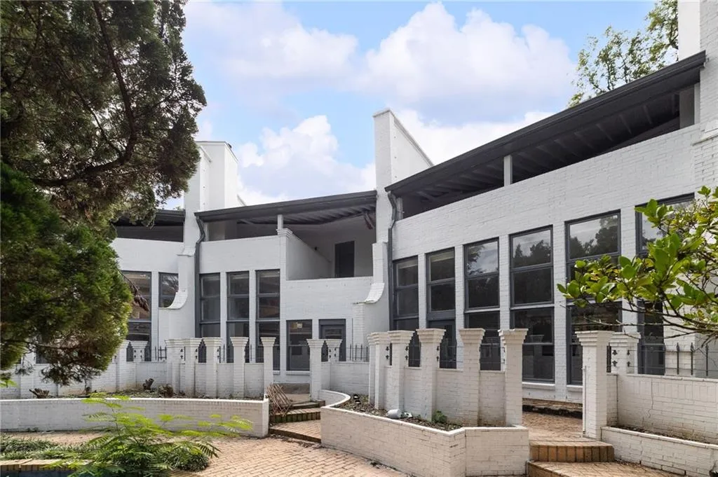 White brick exterior, multiple large windows, covered balcony, brick paver hardscaping, and decorative brick pilasters