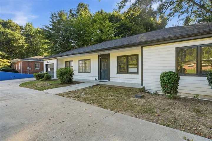 White horizontal siding, dark trim windows, dark front door, and a concrete driveway