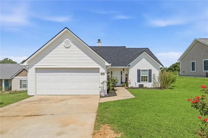 White exterior with a two-car garage, asphalt shingle roof, and a concrete driveway