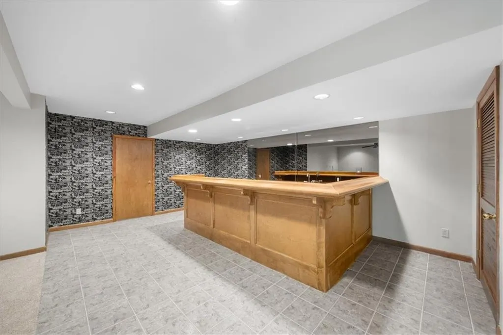 Indoor wet bar featuring baseboards, recessed lighting, wallpapered walls, and an accent wall