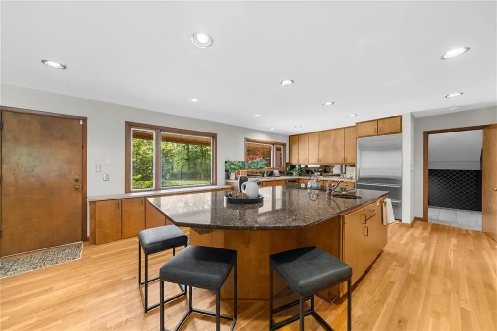 Kitchen featuring built in refrigerator, a sink, brown cabinetry, light wood-style floors, and recessed lighting