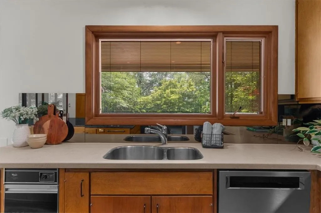 Kitchen with dishwasher, a sink, light countertops, and brown cabinetry