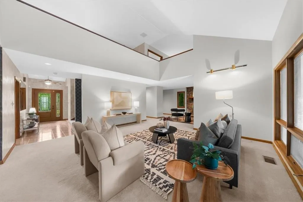 Living area featuring light colored carpet, baseboards, and high vaulted ceiling
