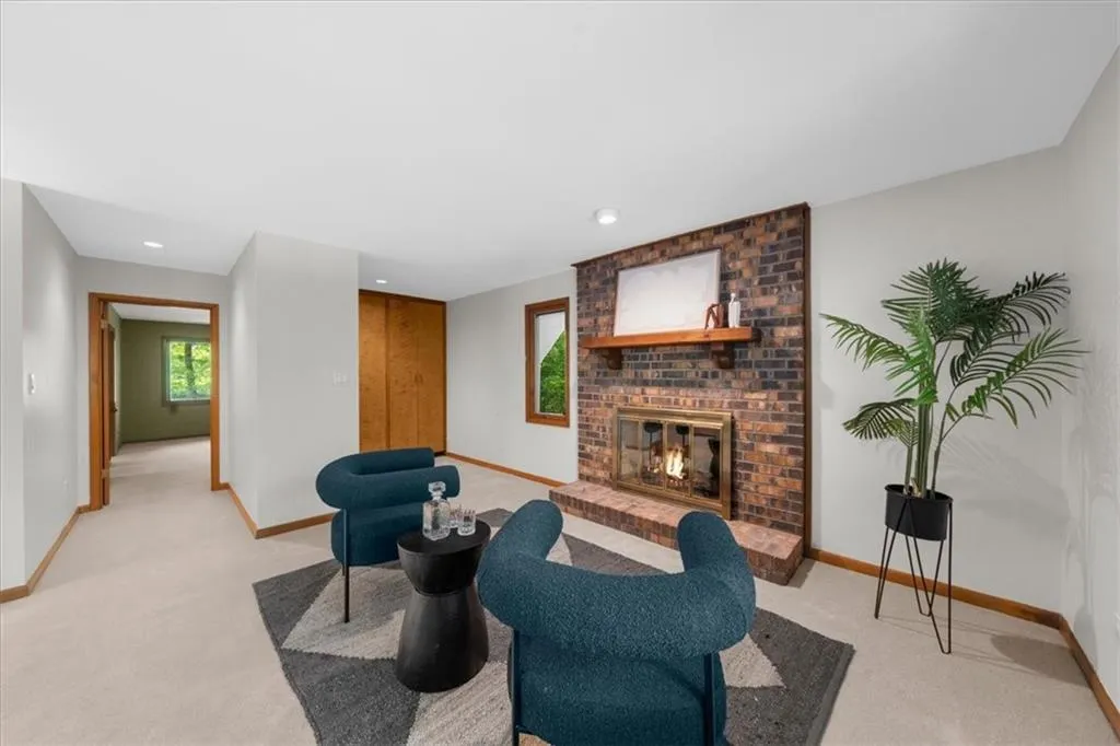 Living room with baseboards, light colored carpet, a fireplace, and recessed lighting