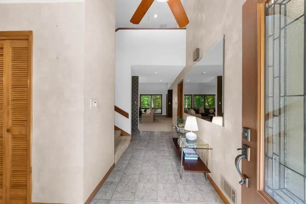 Foyer with stairway, a ceiling fan, a high ceiling, and baseboards