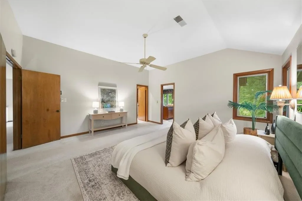 Bedroom featuring light colored carpet, vaulted ceiling, ceiling fan, and baseboards