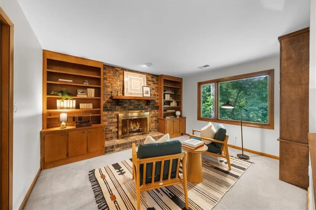 Office area with baseboards, light colored carpet, built in shelves, and a brick fireplace