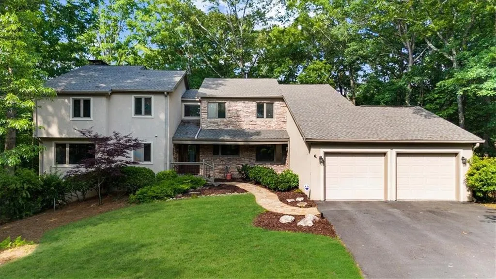 View of front of property featuring stucco siding, a garage, asphalt driveway, and stone siding