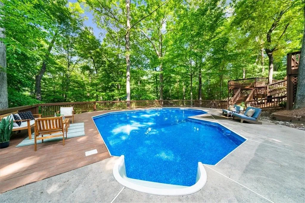 View of pool featuring a wooden deck and stairs