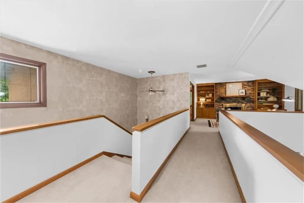 Corridor with light colored carpet, an upstairs landing, built in shelves, and baseboards