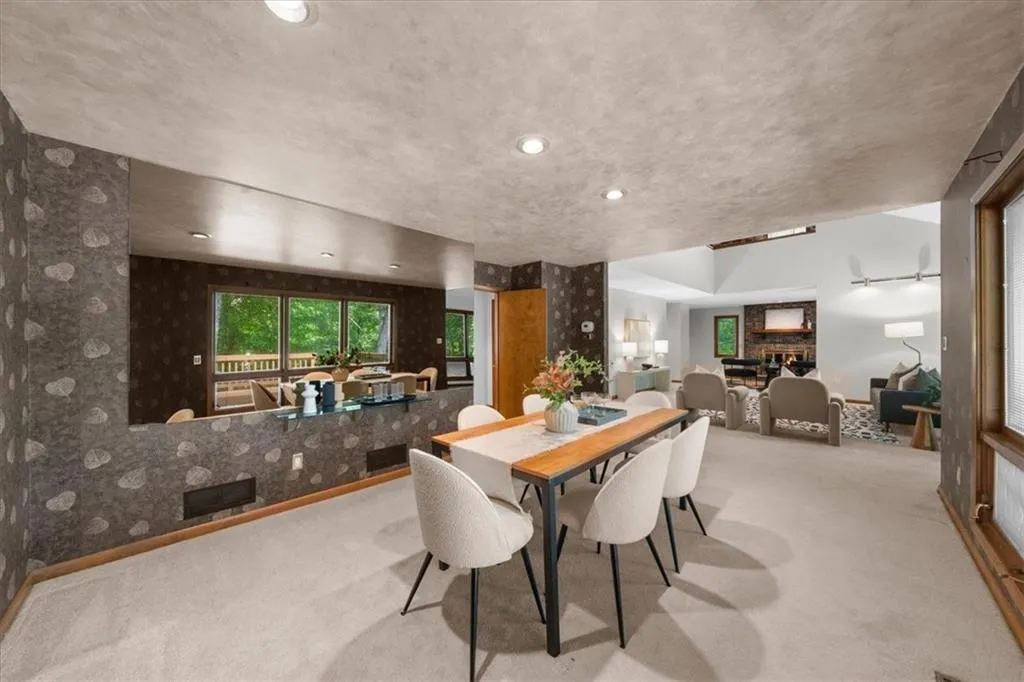 Carpeted dining room featuring wallpapered walls, baseboards, and a textured ceiling