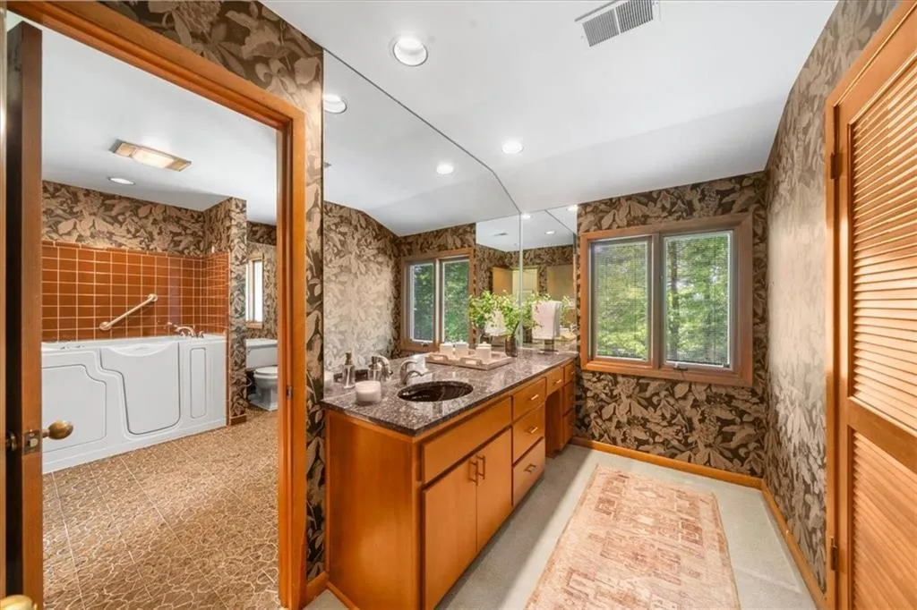 Bathroom featuring toilet, wallpapered walls, a bath, vanity, and recessed lighting
