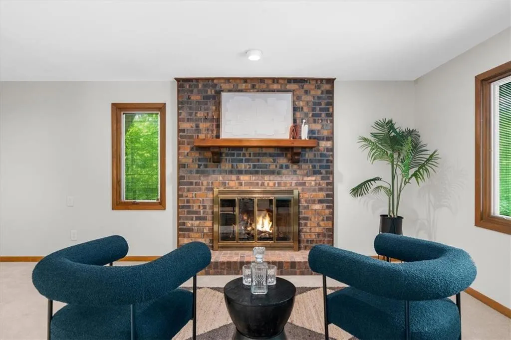 Living room with carpet floors, a brick fireplace, and baseboards