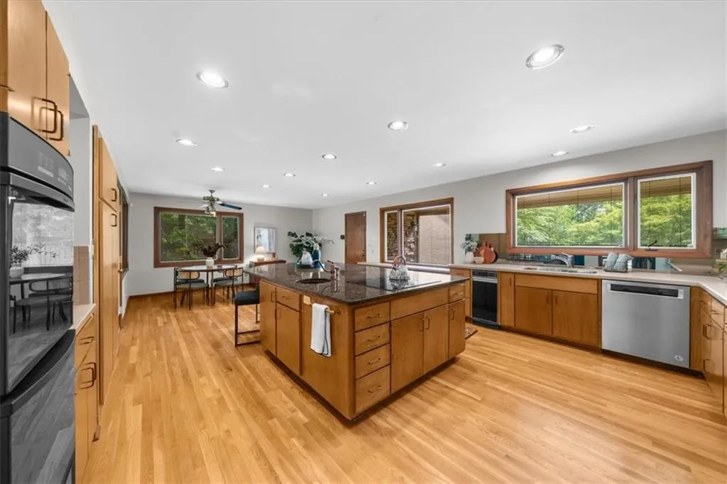 Kitchen with dishwasher, a sink, brown cabinetry, light wood-style flooring, and recessed lighting