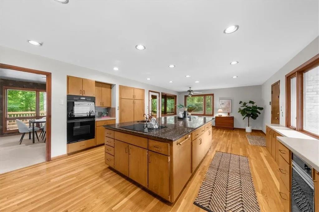 Kitchen with black appliances, light wood finished floors, a center island, recessed lighting, and ceiling fan