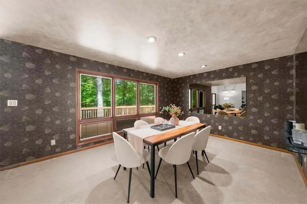 Dining room with wallpapered walls, baseboards, and carpet flooring
