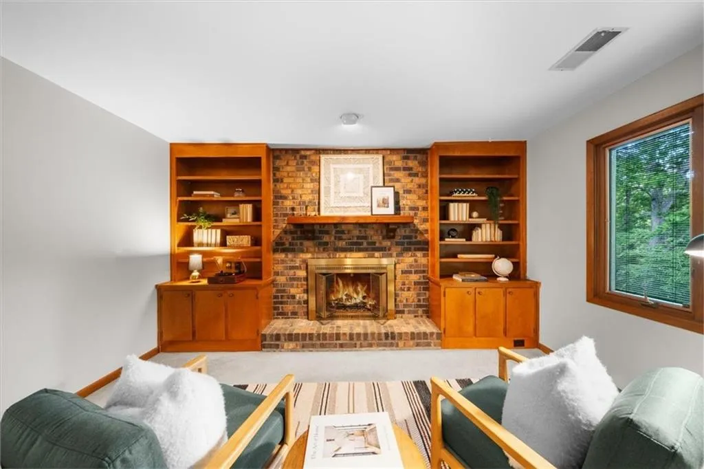 Living area with built in shelves, a fireplace, and baseboards