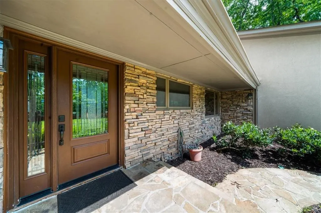 Property entrance with stone siding, stucco siding, and a porch