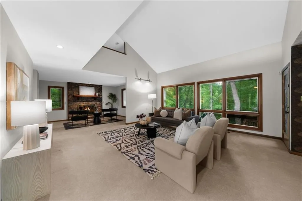 Living area with carpet flooring, a large fireplace, high vaulted ceiling, and baseboards