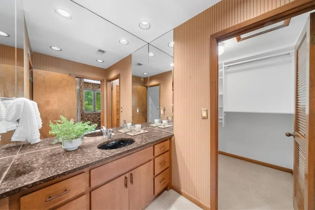 Bathroom featuring baseboards, recessed lighting, vanity, wallpapered walls, and a spacious closet