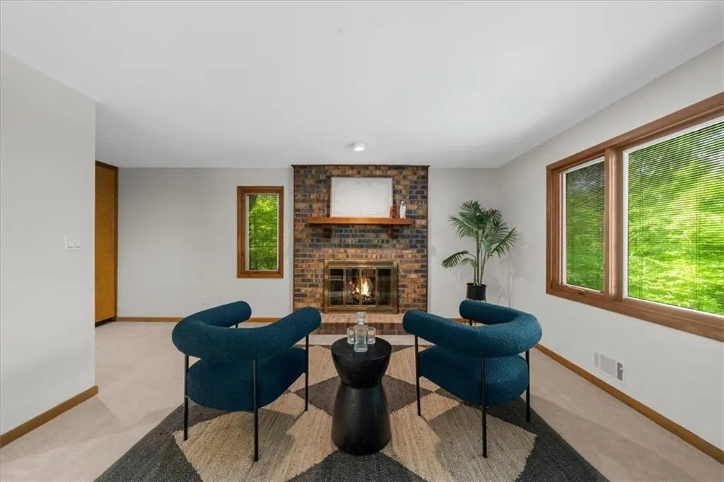 Living room featuring baseboards, a fireplace, light colored carpet, and plenty of natural light