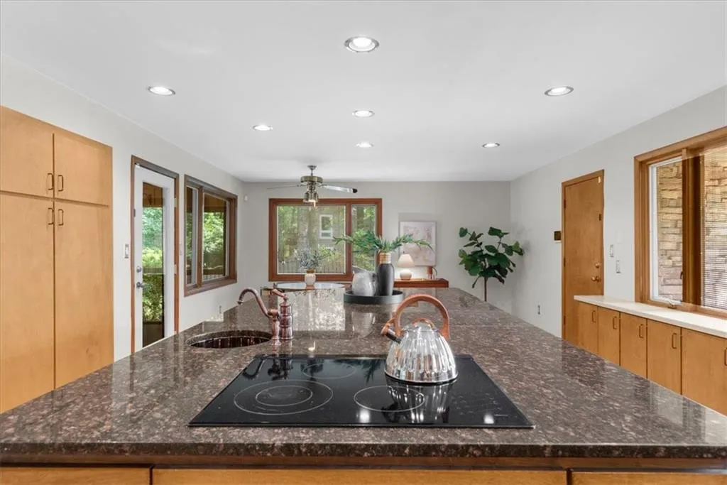 Kitchen with a sink, black electric stovetop, recessed lighting, a spacious island, and dark stone counters