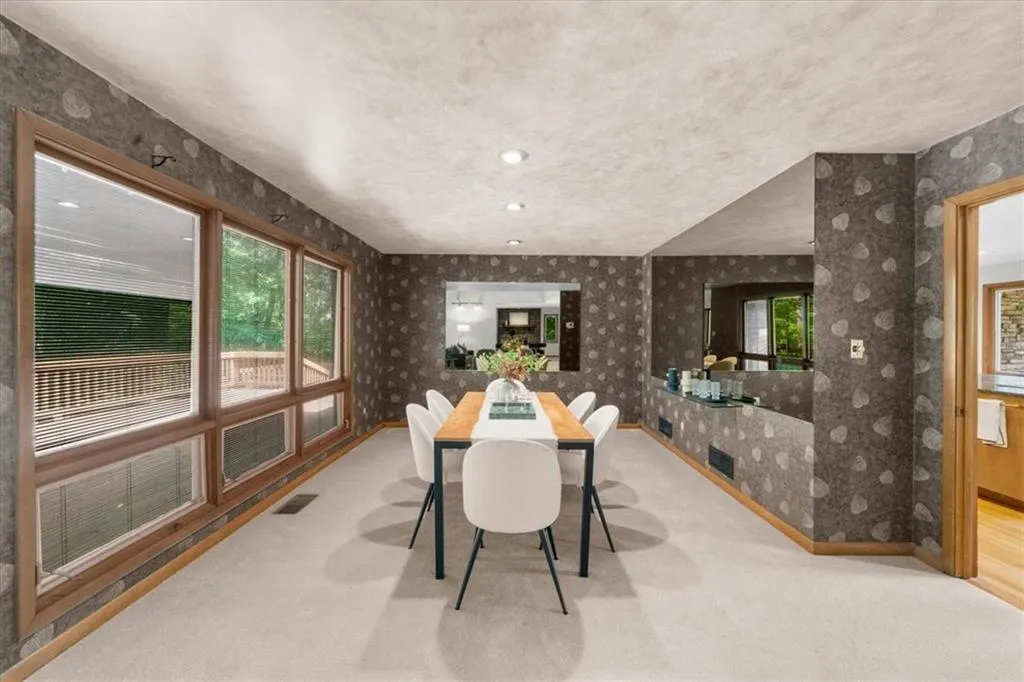 Carpeted dining space with wallpapered walls, baseboards, and recessed lighting