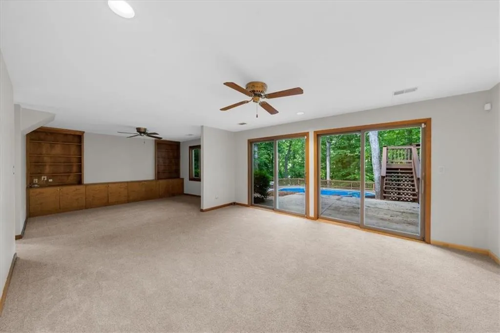 Empty room with a ceiling fan, carpet, and baseboards