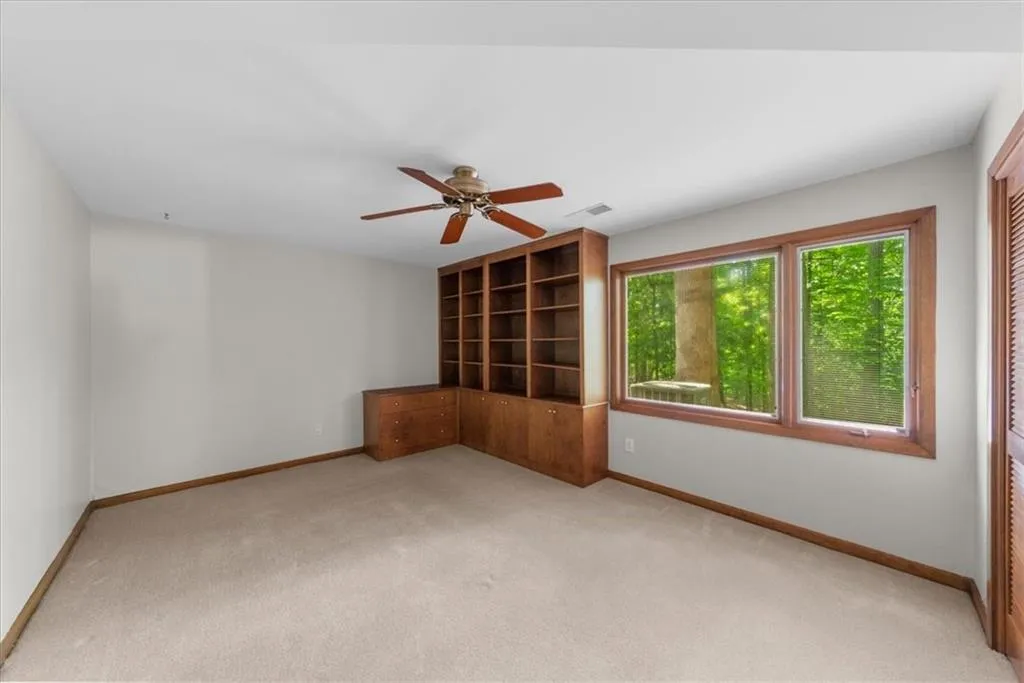 Spare room featuring light colored carpet, baseboards, and ceiling fan