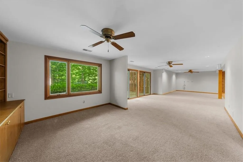 Unfurnished living room with ceiling fan, light carpet, and baseboards