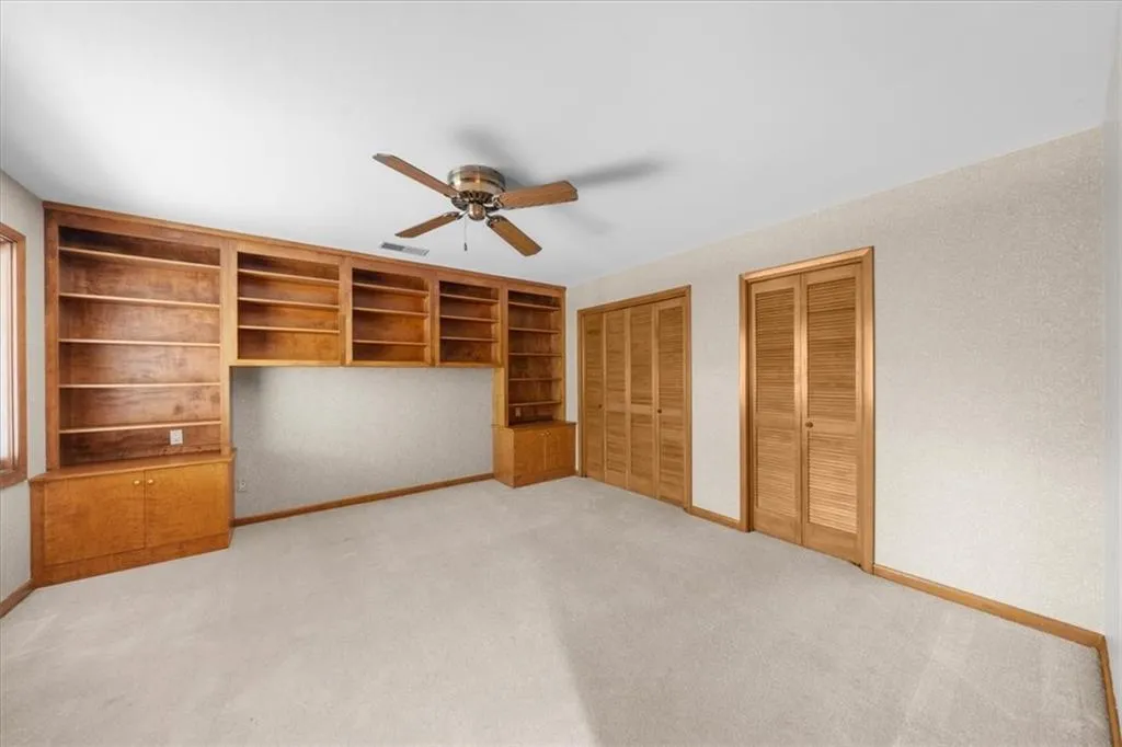 Unfurnished bedroom with multiple closets, baseboards, light colored carpet, and a ceiling fan