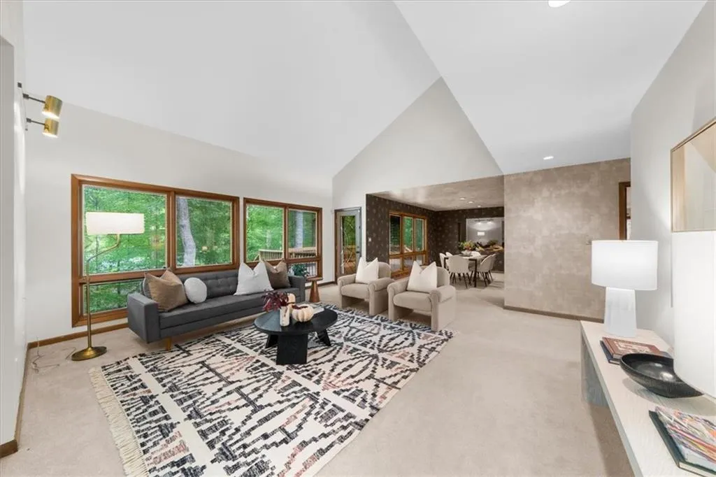 Carpeted living area featuring high vaulted ceiling and baseboards