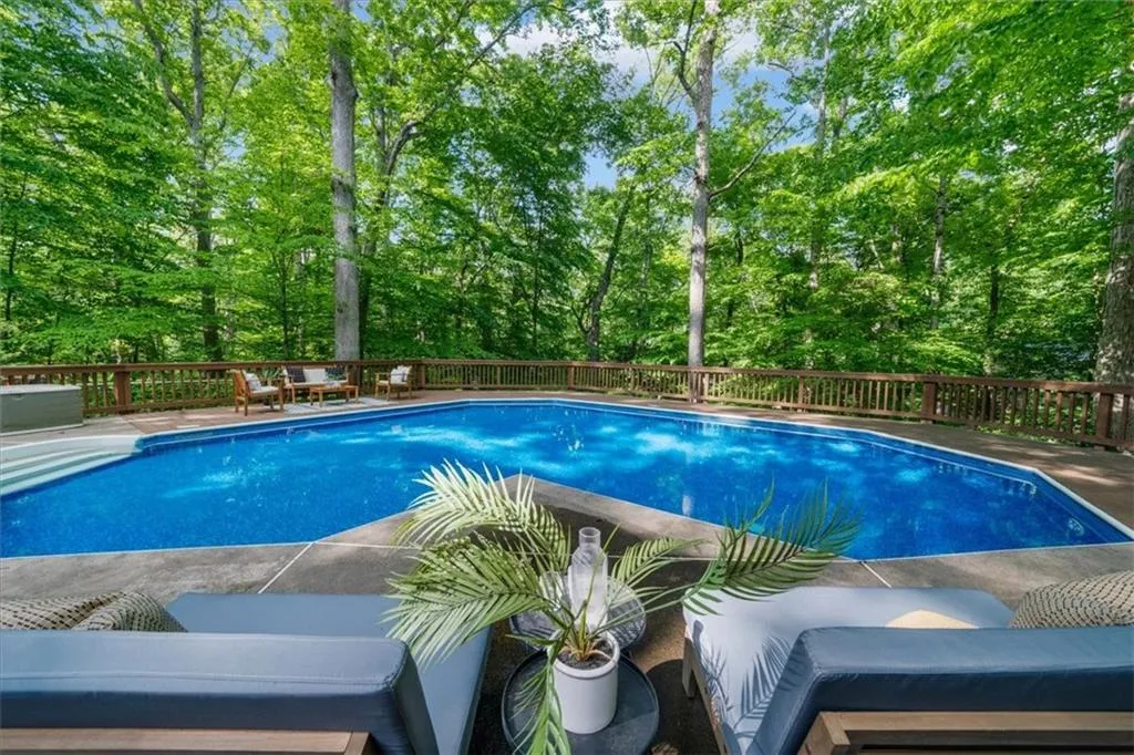 View of swimming pool featuring view of scattered trees and a wooden deck