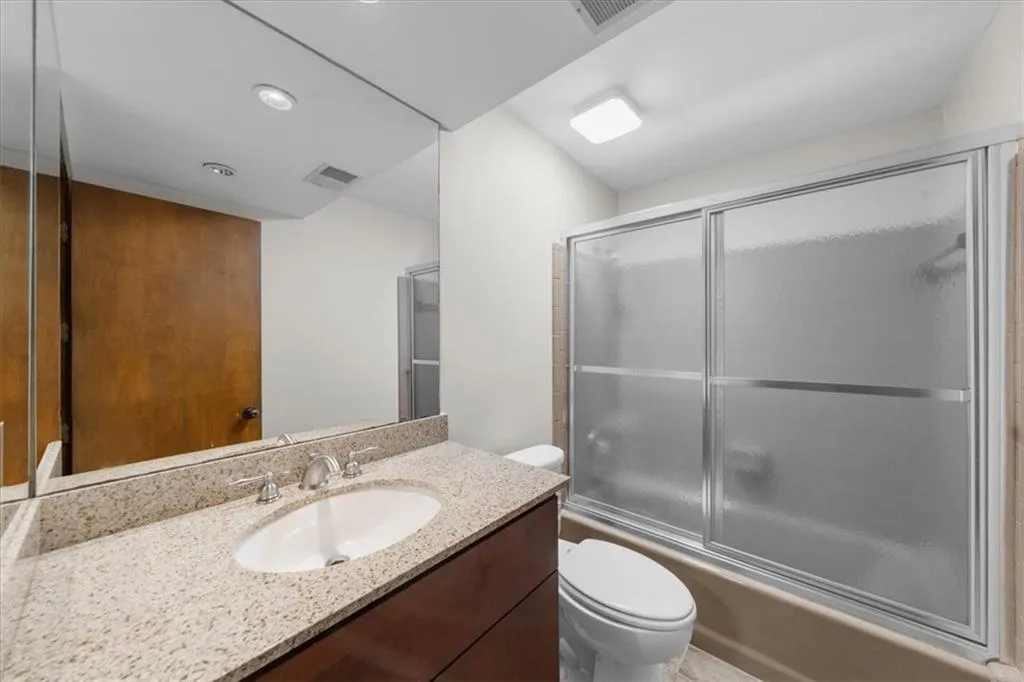 Full bath with toilet, vanity, and combined bath / shower with glass door