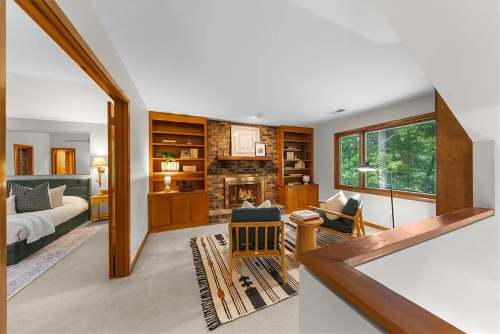 Living room with built in shelves, light carpet, a brick fireplace, and baseboards