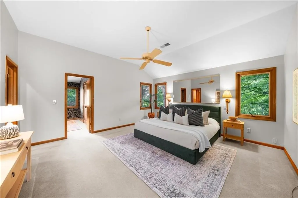 Bedroom featuring light colored carpet, multiple windows, lofted ceiling, and baseboards