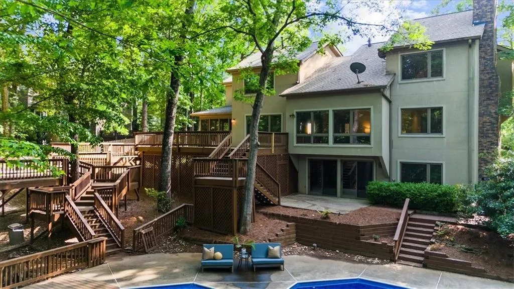 Rear view of property featuring stairs, a deck, a patio, stucco siding, and roof with shingles