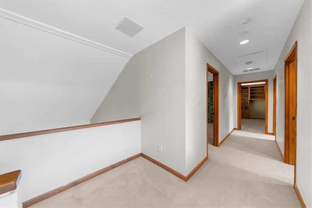 Hall with light colored carpet and baseboards