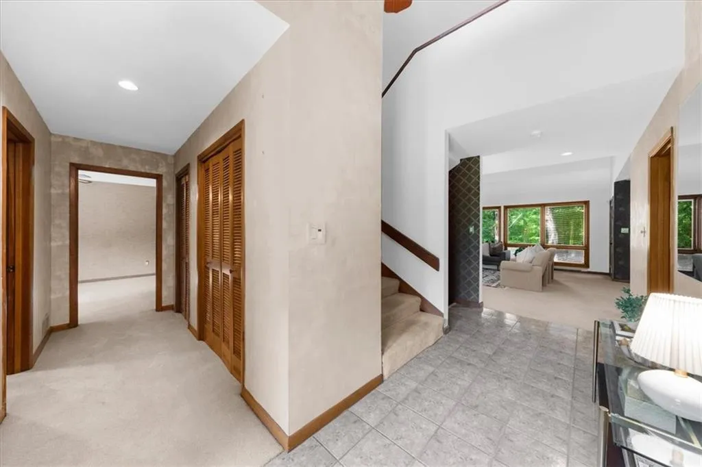 Hallway featuring light carpet, stairs, baseboards, and recessed lighting