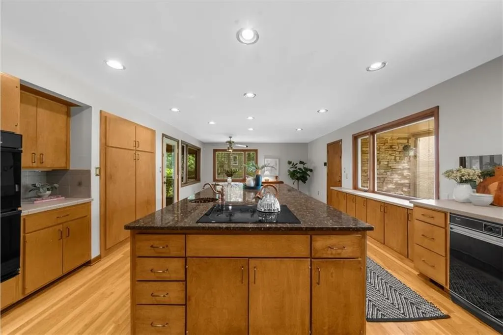 Kitchen featuring black appliances, light wood finished floors, a sink, recessed lighting, and decorative backsplash