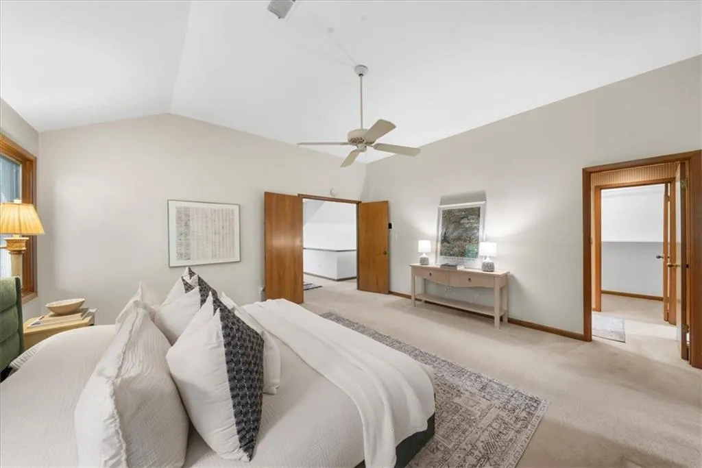 Bedroom with light carpet, lofted ceiling, a ceiling fan, multiple windows, and baseboards