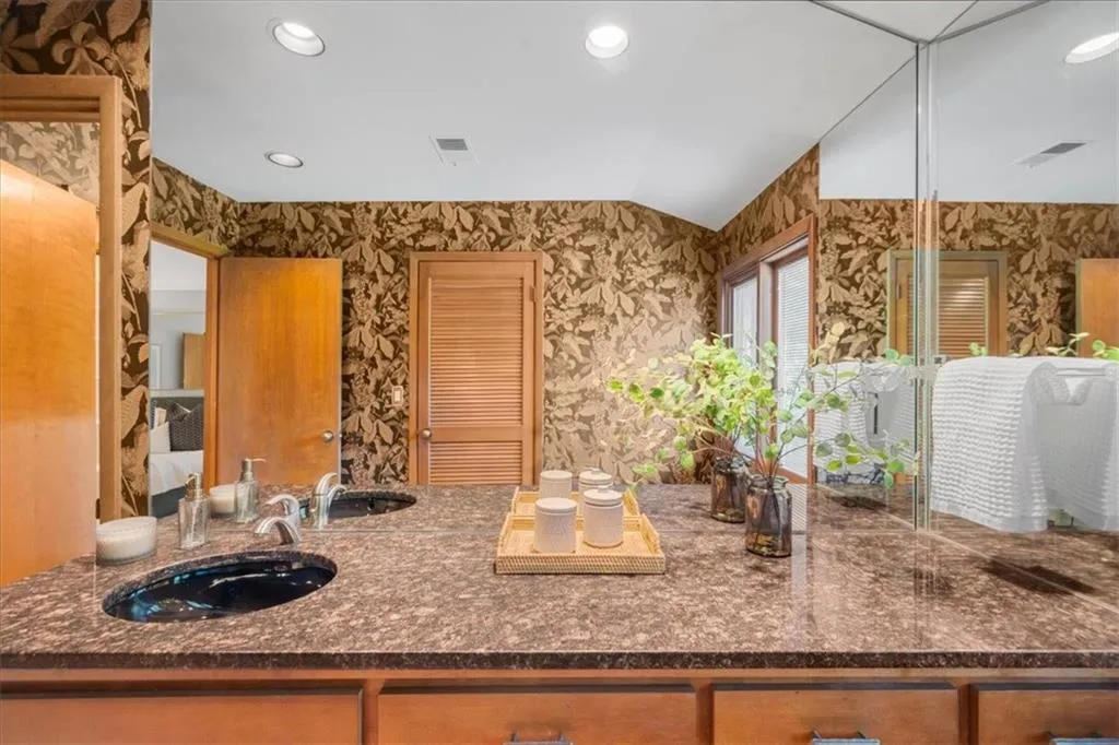 Bathroom featuring wallpapered walls, recessed lighting, vaulted ceiling, and vanity