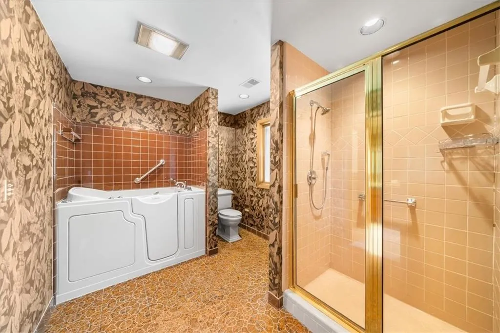 Full bath featuring toilet, a stall shower, a garden tub, and recessed lighting