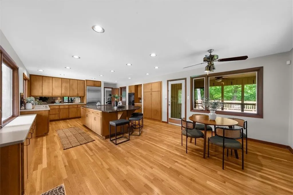 Kitchen with brown cabinetry, stainless steel refrigerator, a kitchen breakfast bar, light wood-style floors, and a kitchen island with sink