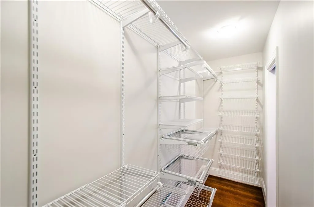 Walk in closet with dark wood-type flooring