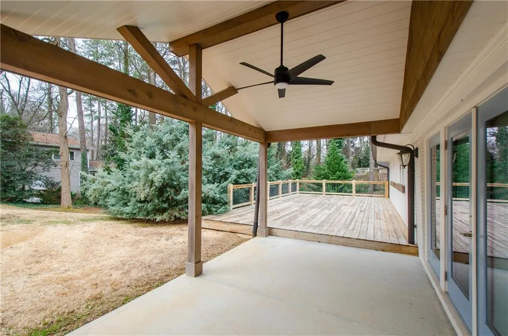 Unfurnished sunroom featuring a ceiling fan, a wooden deck, and lofted ceiling with beams