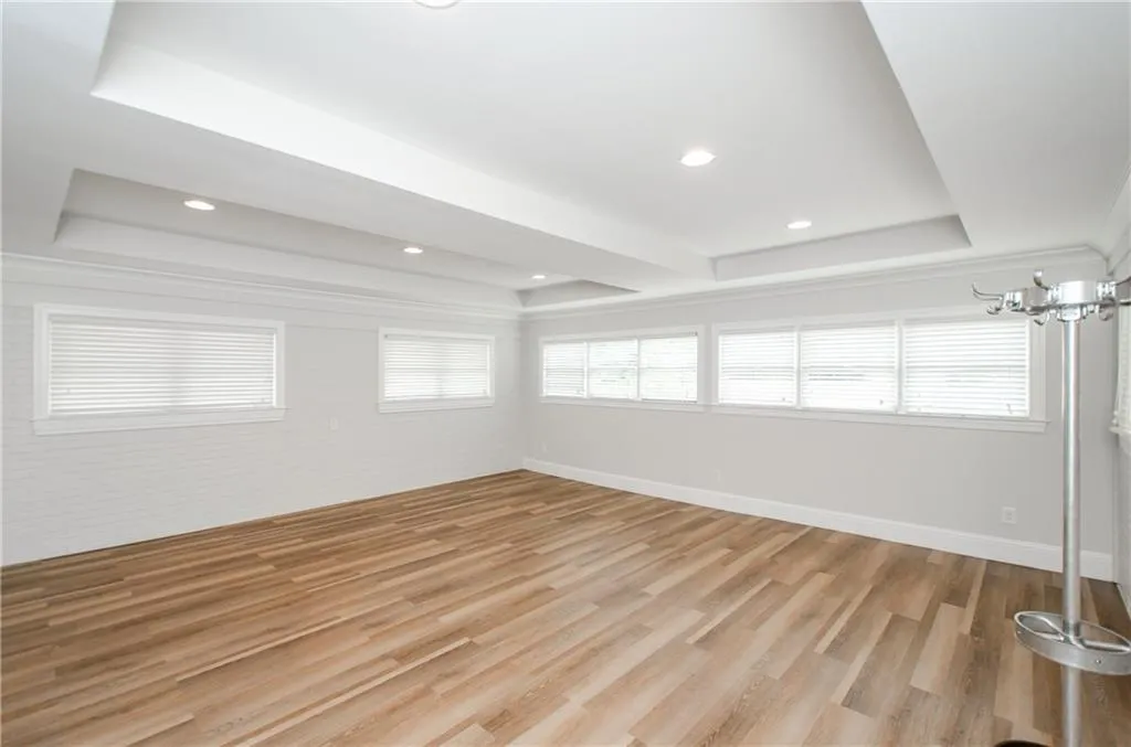 Spare room featuring a raised ceiling, light wood finished floors, plenty of natural light, and recessed lighting